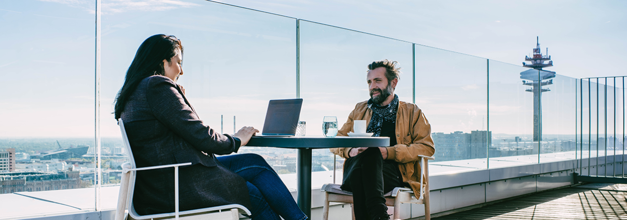 Mann und Frau sitzen auf einer Hochhaus-Terrasse