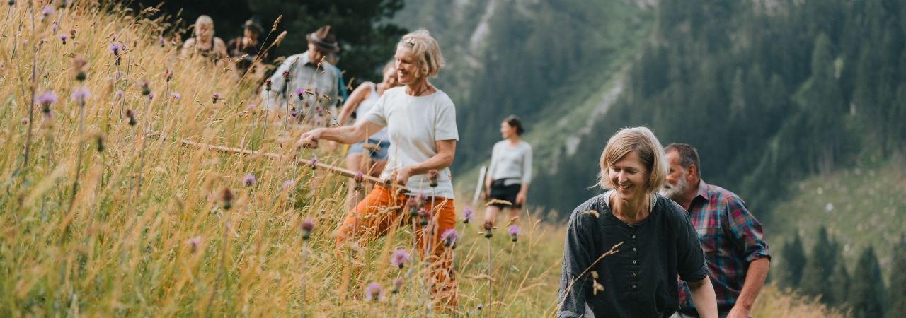 Мъже и жени косят ръчно планинско пасище